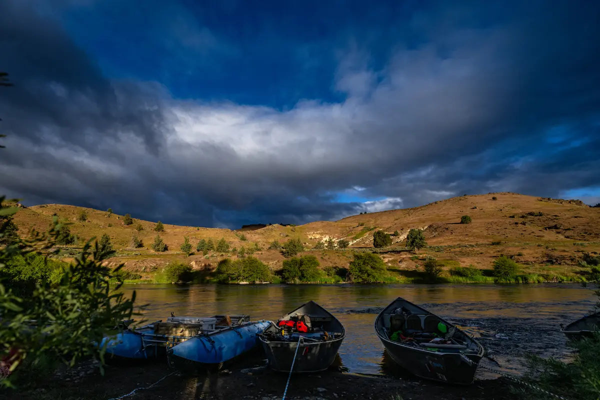 Boats on a riverbank with a dramatic sky and landscape